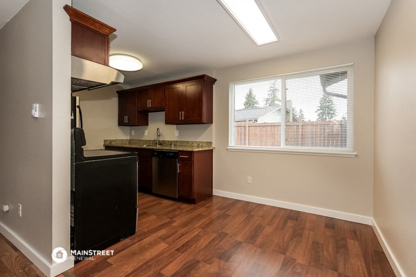 an empty kitchen with a large window and wood flooring