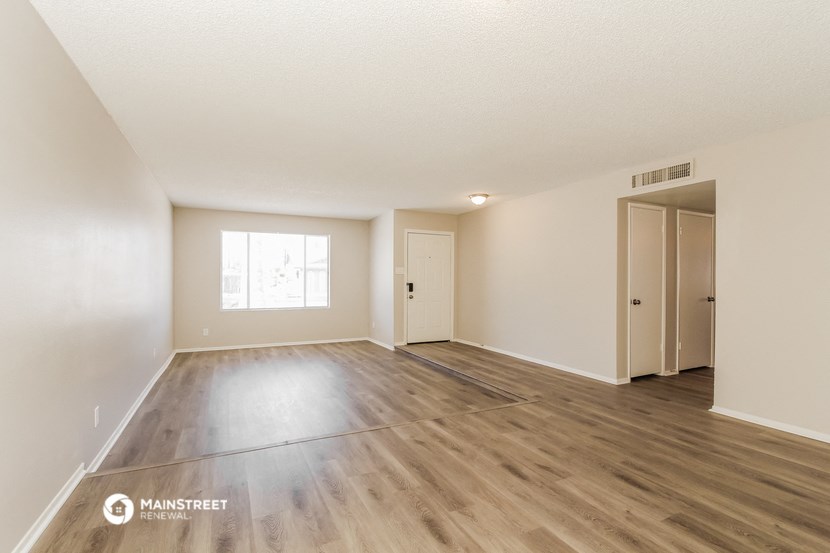 the spacious living room with hardwood flooring and white walls