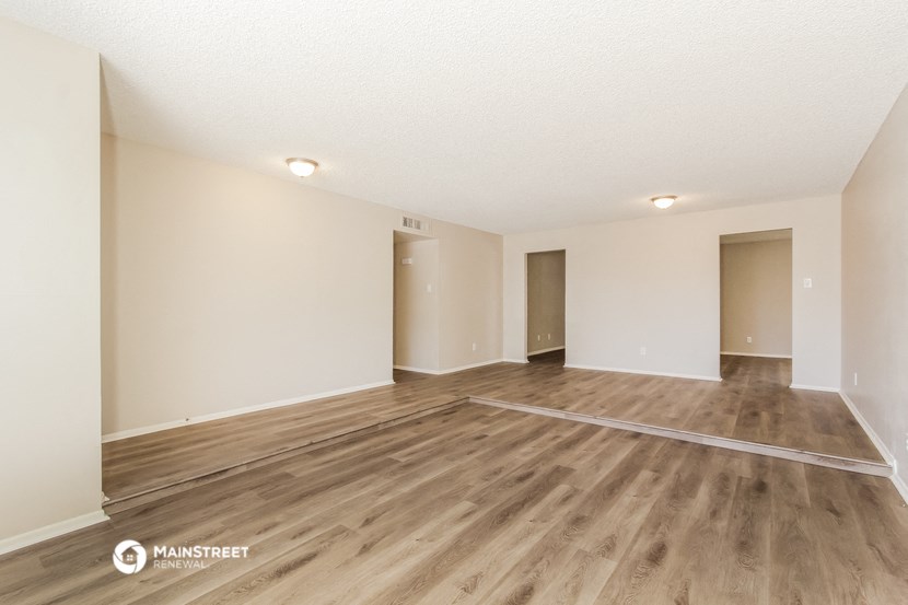 the spacious living room with hardwood flooring and white walls