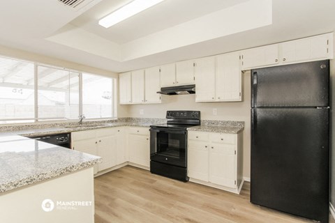 a kitchen with white cabinets and black appliances