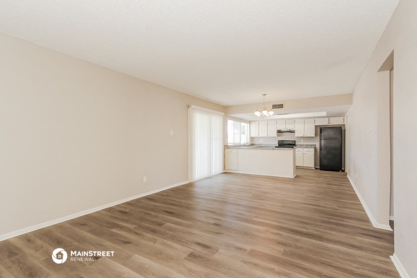 the spacious living room and kitchen of an apartment