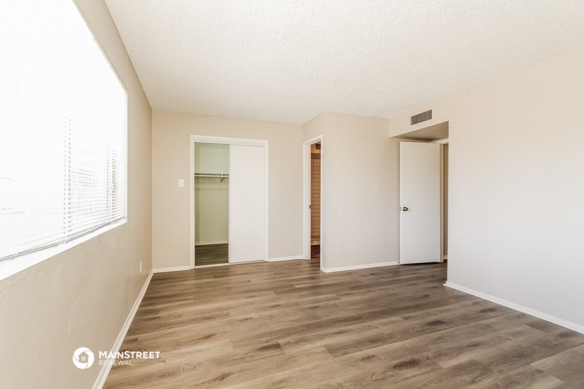 a spacious living room with white walls and wood flooring