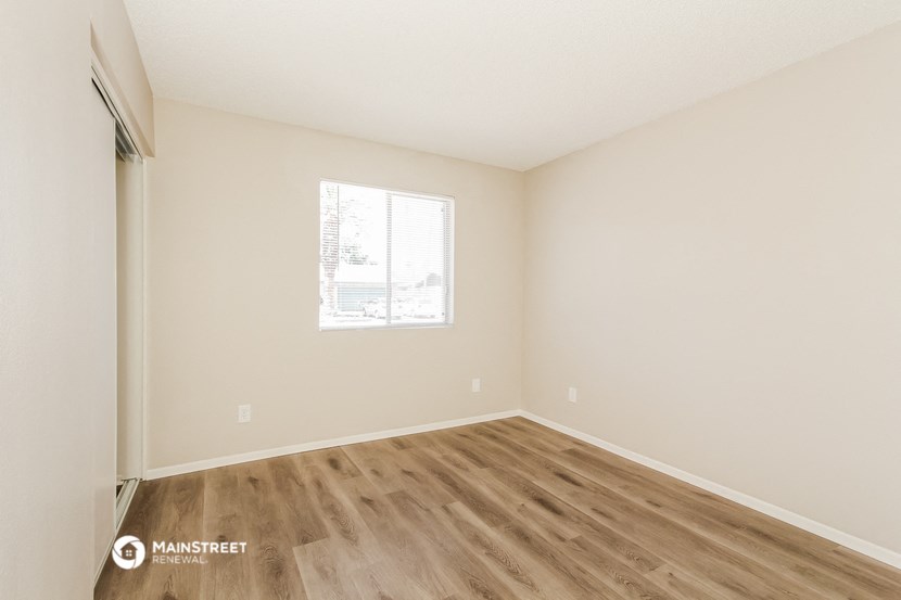the spacious living room with wood flooring and a window