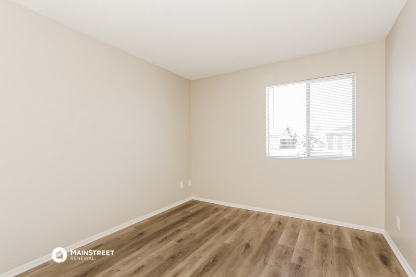 the spacious living room with wood flooring and a window