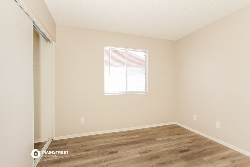 an empty room with a window and wooden floors