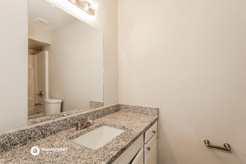 a bathroom with granite counter top and a mirror