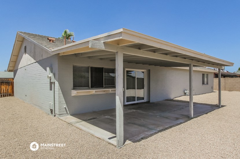 a small gray house with a covered porch and a driveway