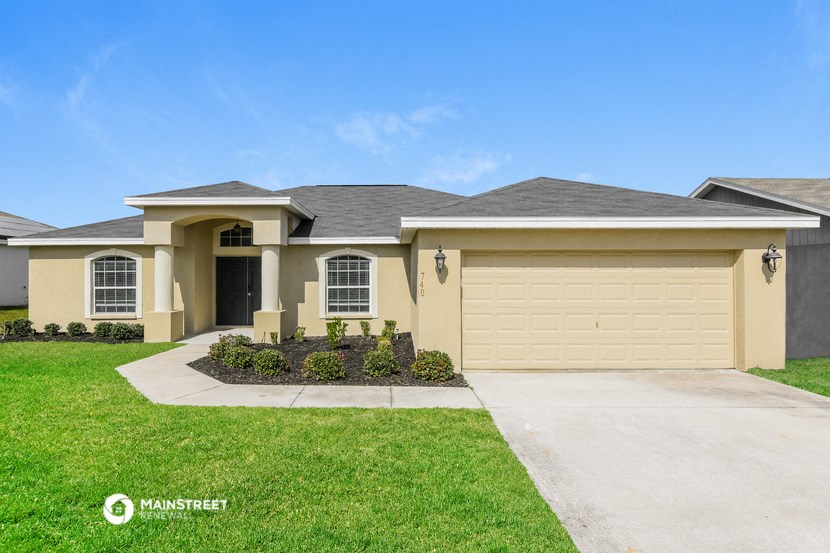 a beige house with a garage door and a lawn