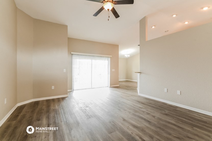 the spacious living room and dining room with hardwood floors and a ceiling fan