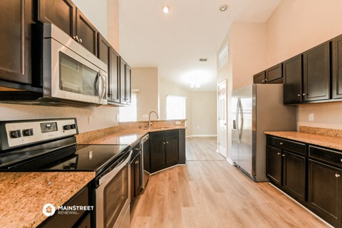 a kitchen with black cabinets and stainless steel appliances and marble counter tops