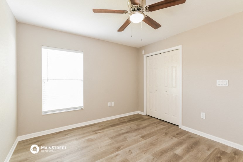 an empty room with a ceiling fan and a window