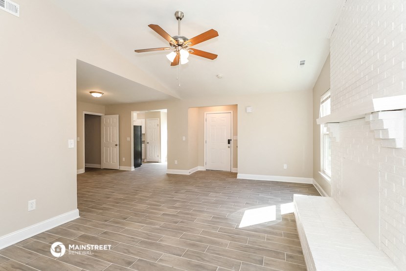an empty living room with a ceiling fan