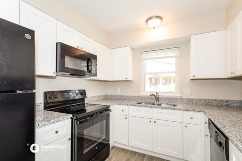 a kitchen with white cabinets and black appliances