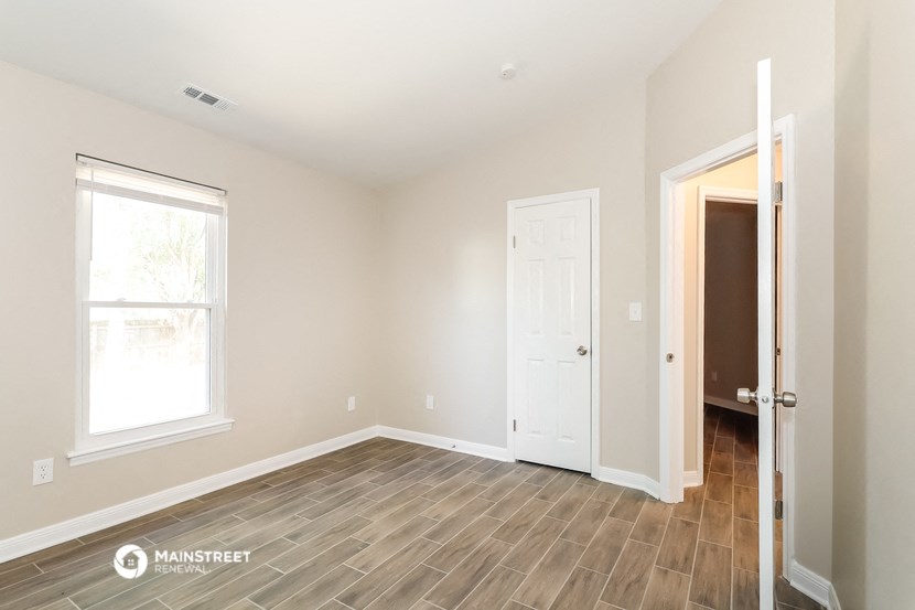 the living room of a new home with wood flooring and a white door