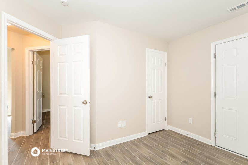 the living room of an apartment with two doors and a hallway