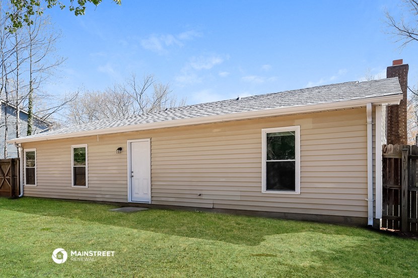 the front of a tan house with a white door and a yard