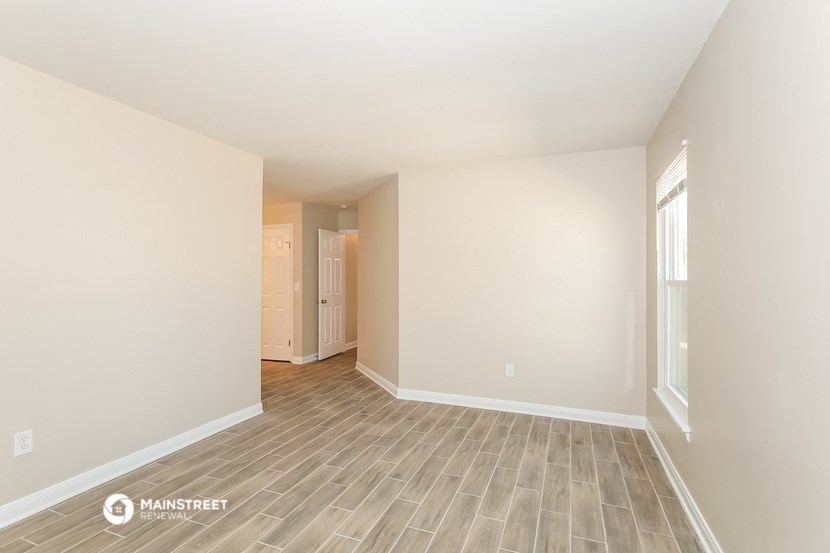the spacious living room with wood flooring and white walls