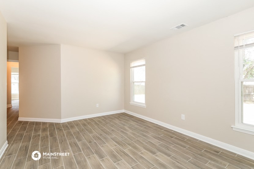 the spacious living room with wood flooring and two windows