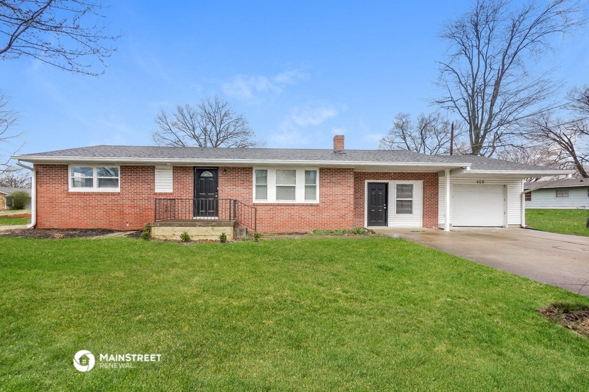 a brick house with a black door and a green lawn