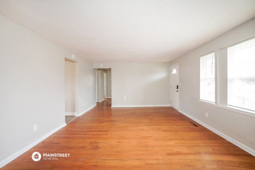 an empty living room with wood flooring and large windows
