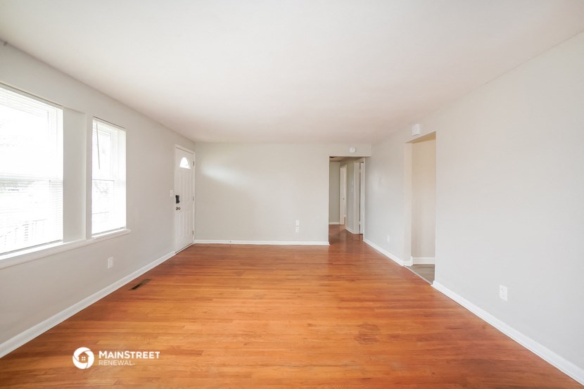 an empty living room with wood floors and white walls