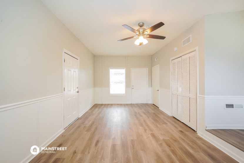 an empty living room with white walls and a ceiling fan