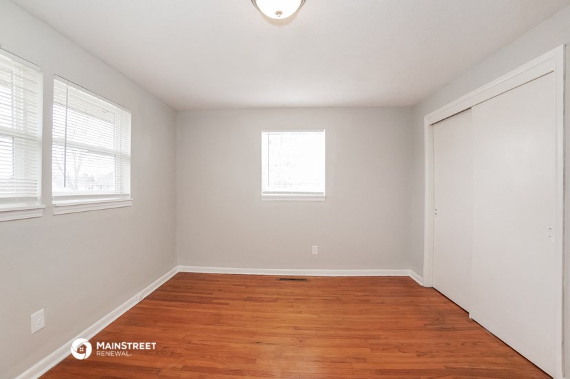 a bedroom with a wood floor and white walls