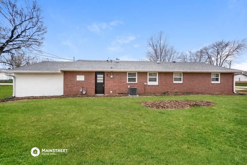 the front of a brick house with a green lawn