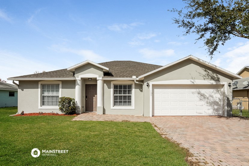 a beige house with a lawn and a garage door