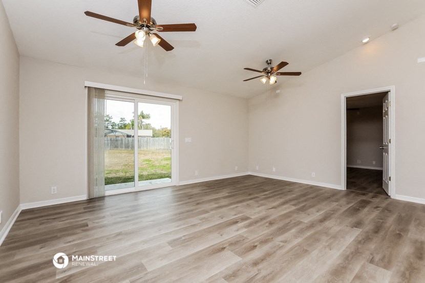 the spacious living room with wood flooring and ceiling fans