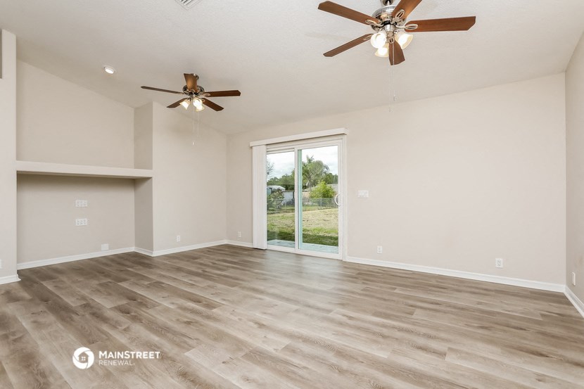 the spacious living room with ceiling fans and a large window