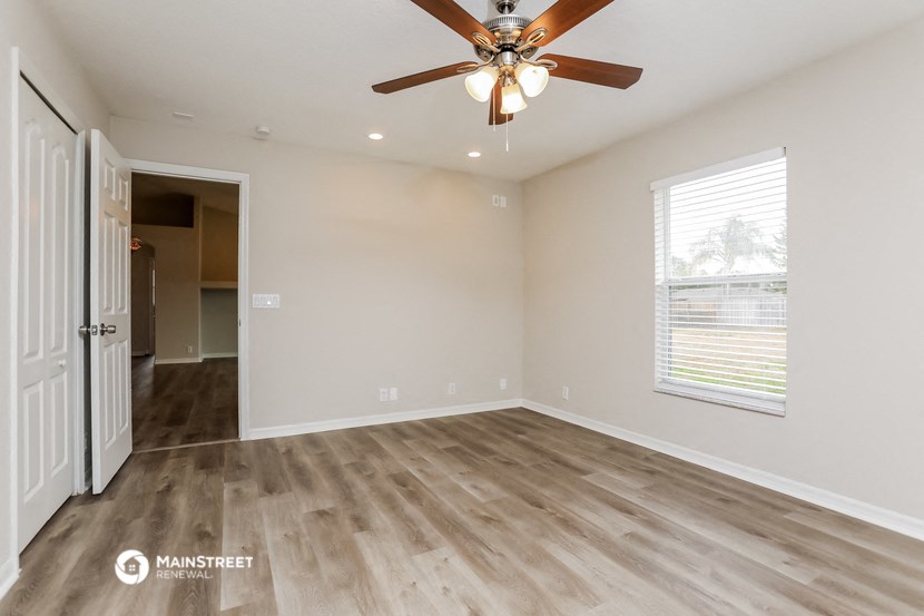 the spacious living room with wood flooring and a ceiling fan
