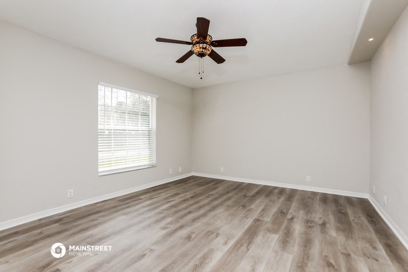 the spacious living room with hardwood floors and a ceiling fan