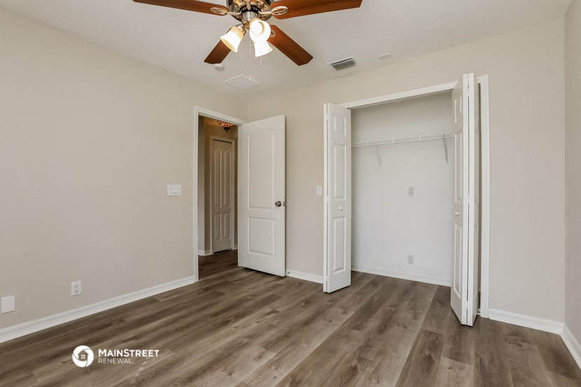 the living room of an apartment with wood flooring and a ceiling fan