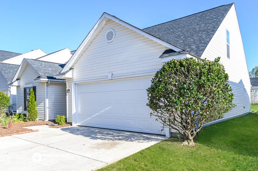 a white house with a white garage door and a small tree