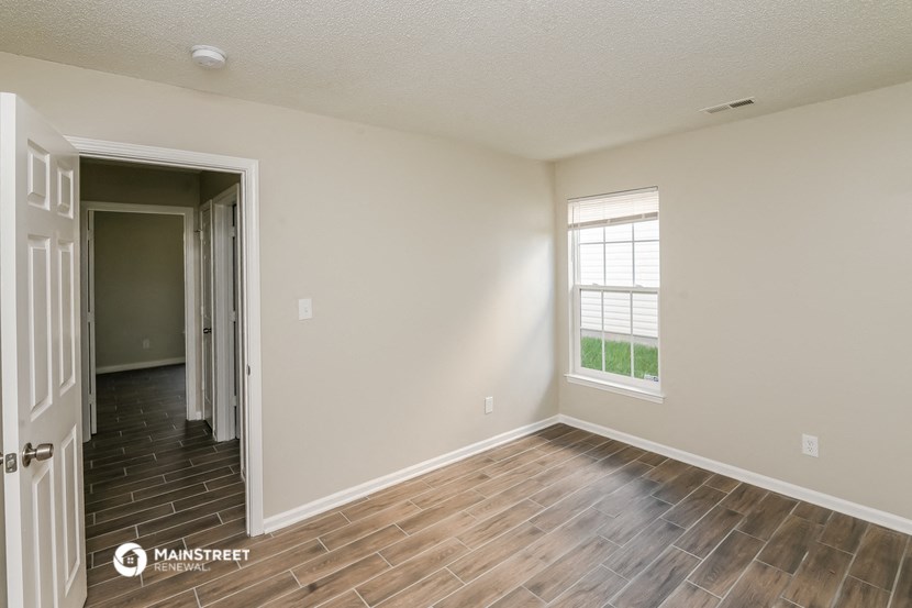 the spacious living room with wood flooring and a window