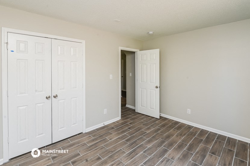 the living room of an apartment with two closets and a door to the hallway