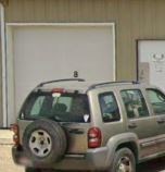 A silver SUV is parked in front of a white garage door.
