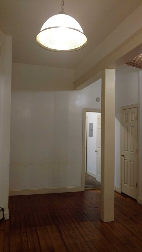 A hallway with a light hanging from the ceiling and a door at the end.