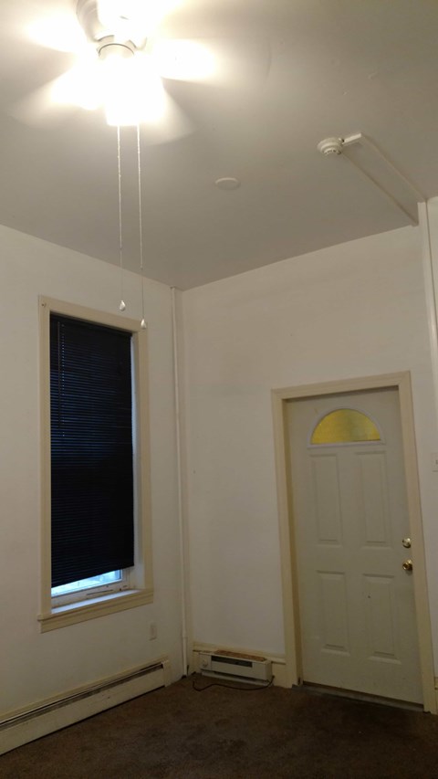 A room with a white door and a window with blinds.