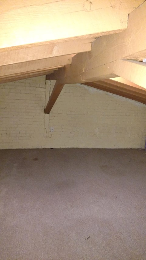A white brick wall with a wooden beam.