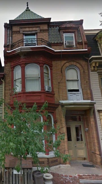 A red and brown Victorian style house with a green roof.