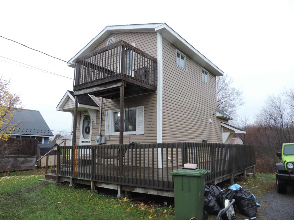 the back of our house with a deck and a garbage can