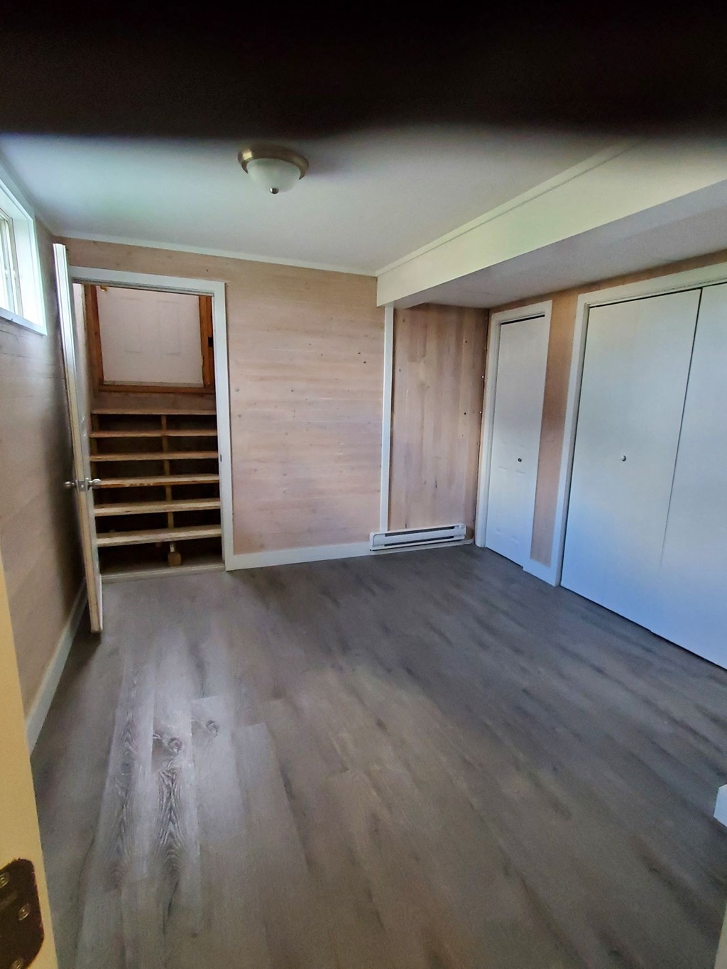 a room with wooden floors and a closet and a staircase