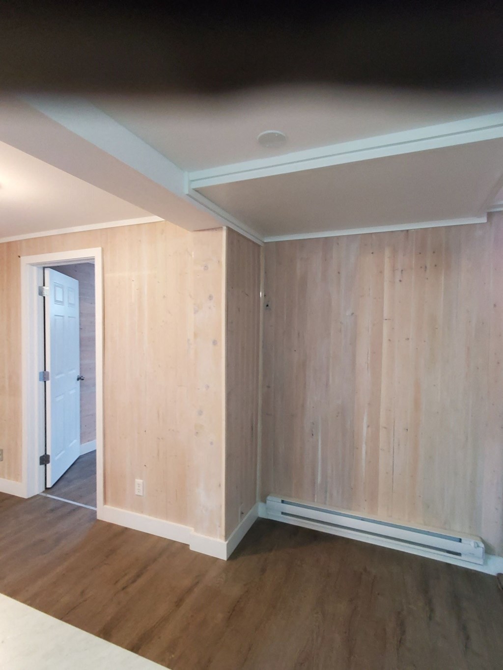 an empty room with wooden floors and a white door