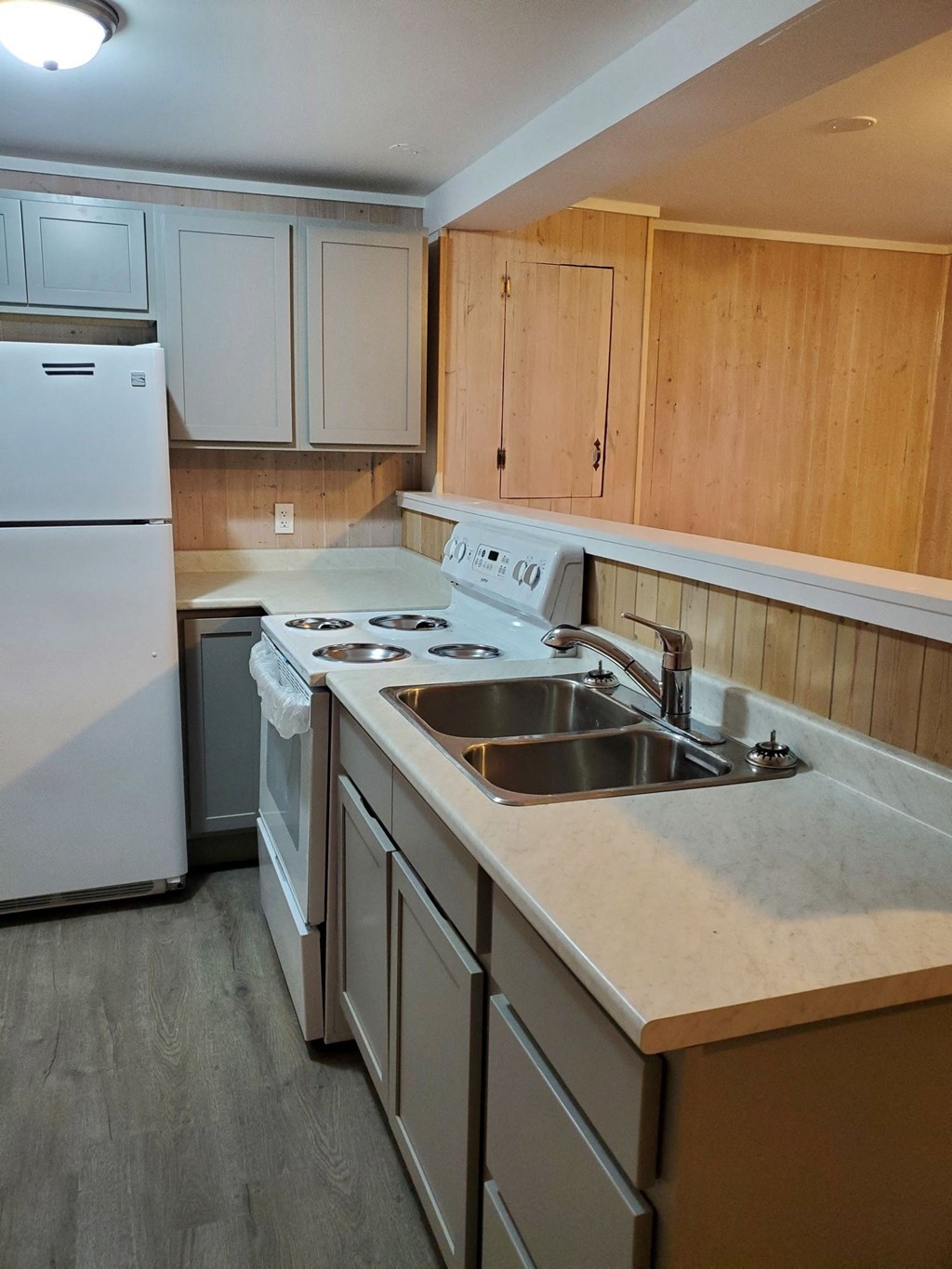 an empty kitchen with white appliances and wooden cabinets