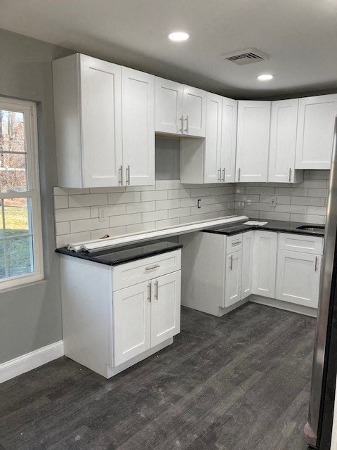 A kitchen with white cabinets and a black countertop.