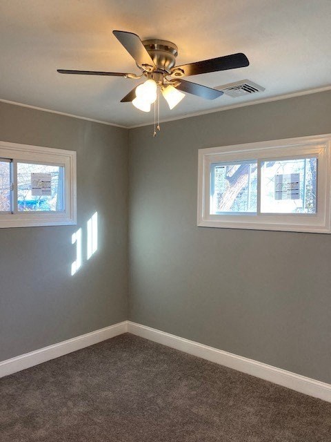 A room with a ceiling fan and two windows.