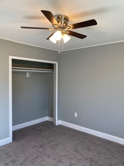 A room with a ceiling fan and carpeted floor.