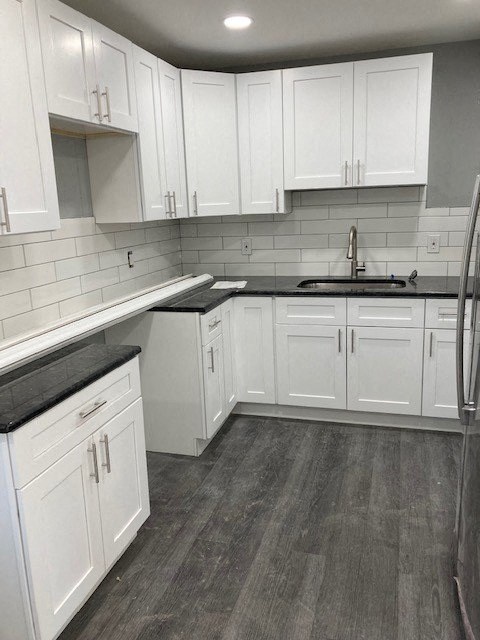 A kitchen with white cabinets and a black countertop.